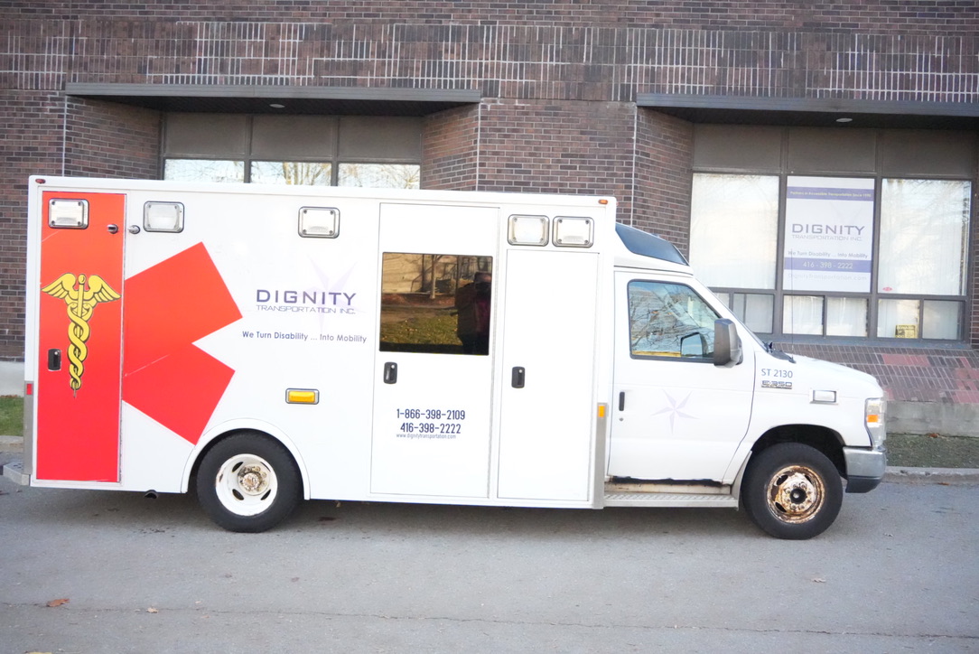 White wheelchair accessible non-emergency transport van with side lift parked in an accessible loading zone outside a hospital